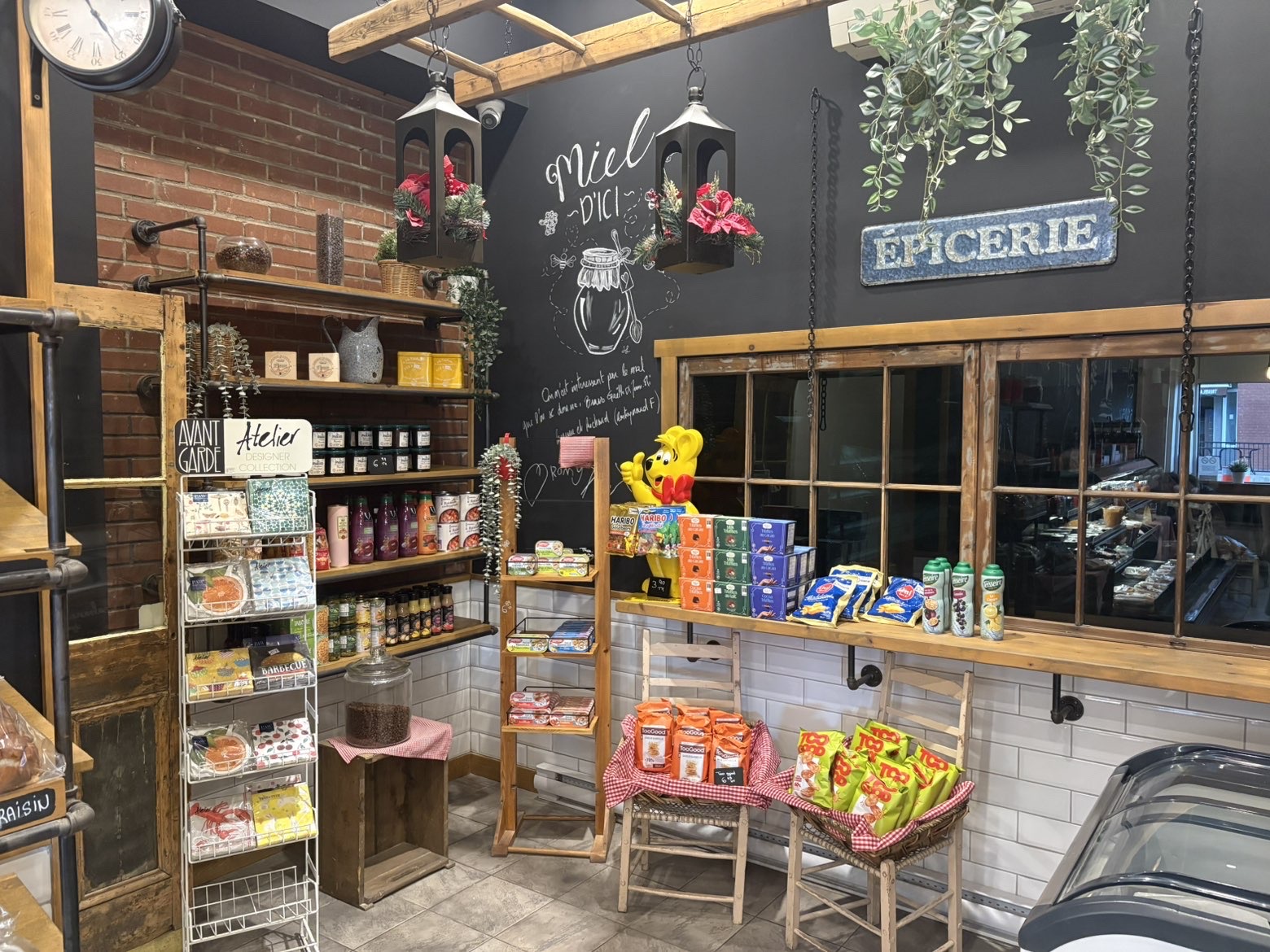 Section épicerie avec mur « Miel d'ici », étagères en bois et lanternes suspendues